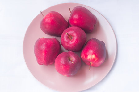 Fresh red apples in pink plate are isolated on white background.の写真素材