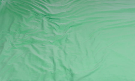 Green crumpled or wrinkled bedding sheet or blanket with pattern after guest's use was taken in hotel, resort room with copy space. Untidy blanket background textureの写真素材