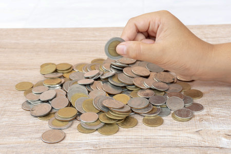 Child or kid hand is holding coin over coin stack. Concept of saving money for the future or money...