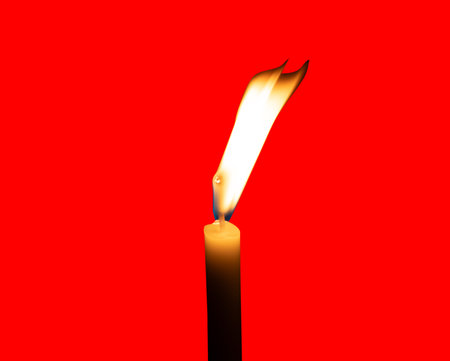 A single burning candle flame or light glowing on a small yellow candle is isolated on red background with clipping path.の写真素材