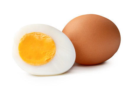 Front view of raw brown chicken eggs and cooked or boiled chicken egg with egg yolk in half in stack is isolated on white background with clipping path.の写真素材