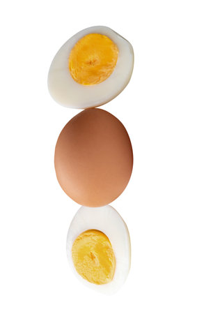 Top view of raw chicken egg and peeled cooked or boiled egg with egg yolk in two halves in stack is...