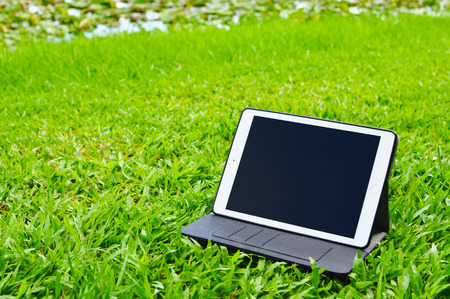 Tablet on green grass background with copy spaceの写真素材