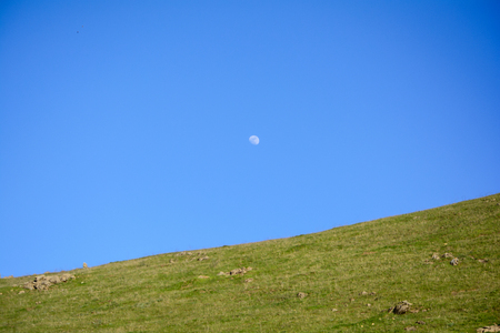 Moon in Blue Sky Above Mountain in the Springの写真素材