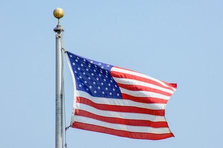 USA Flag Flying in the Wind under Blue Skyの写真素材