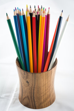 Wooden pencil holder with colored pencils against white backgroundの写真素材