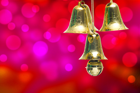Gold christmas jingle bells on a red bokeh background.の写真素材