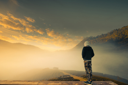 A man stand in the Beautiful landscape of green tea plantation in the morning.
