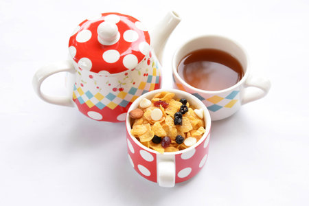 Teapot, cup of tea and delicious cornflakes isolated on whiteの写真素材