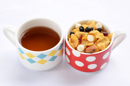 Teapot, cup of tea and delicious cornflakes isolated on whiteの写真素材
