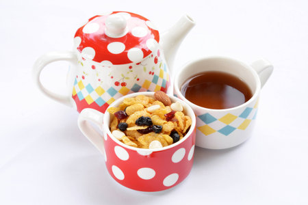Teapot, cup of tea and delicious cornflakes isolated on whiteの写真素材