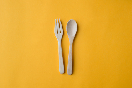 Wooden spoon and fork on yellow paper backgroundの写真素材