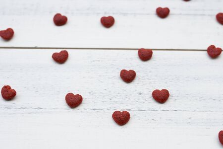 Red little hearts on white wooden background, selective focus on the heart in the centerの写真素材