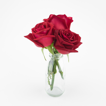 Red roses bouquet in glass vase on white backgroundの写真素材