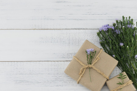 Brown gift boxes with purple cutter flowers bouquet on white wood background with copy spaceの写真素材