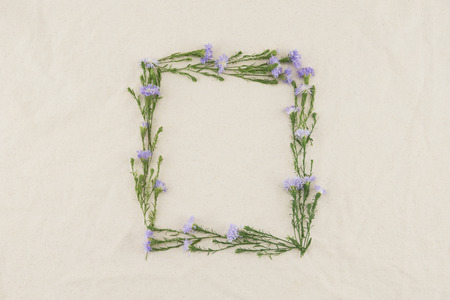 Square frame made from purple cutter flowers on white muslin fabric with copy spaceの写真素材