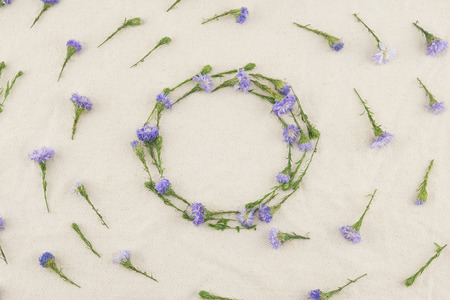 Round wreath of purple cutter flowers on white muslin fabric with copy space in the centerの写真素材