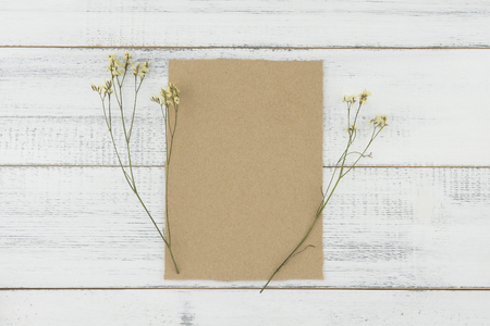 Blank brown card decorated with yellow limonium caspia flowers on white wood backgroundの写真素材