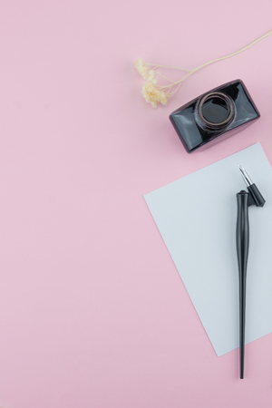 Blank white card, oblique pen and ink decorate with white dried flowers on pastel pink background with copy spaceの写真素材