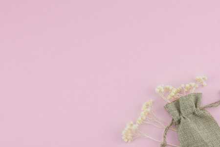 Sackcloth bag with white dried flowers on pastel pink background with copy spaceの写真素材