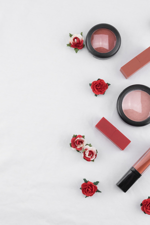 Cosmetics decorate with red rose paper flowers on white fabric with copy spaceの写真素材
