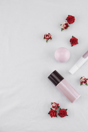 Skincare decorate with red rose paper flowers on white fabric with copy spaceの写真素材