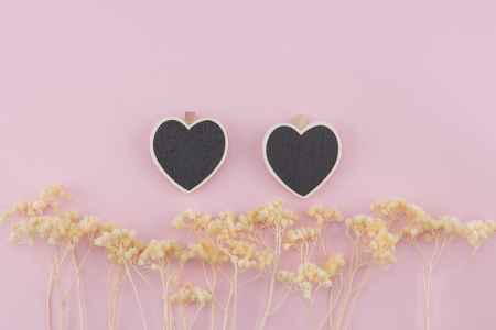 Two heart shape board decorate with white dried flowers on pastel pink backgroundの写真素材