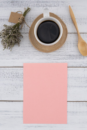 Blank pink card and a cup of coffee with caspia bouquet on white wood background with copy spaceの写真素材