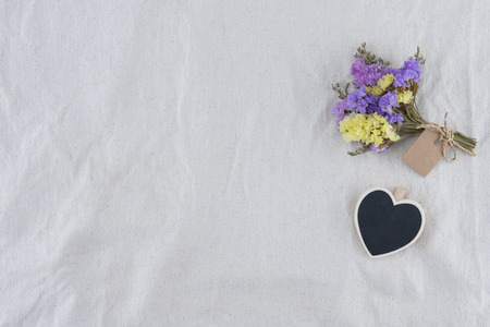 Tiny heart blackboard with statice flowers bouquet with card on white muslin fabric with copy spaceの写真素材