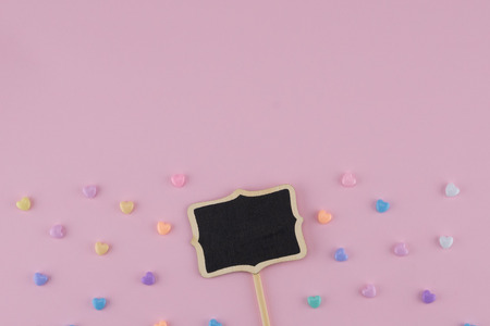 Tiny blackboard sign with pastel heart pattern on pink background with copy spaceの写真素材
