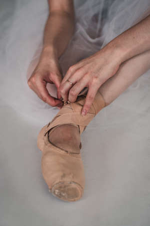 Professional ballerina putting on a pointe shoe