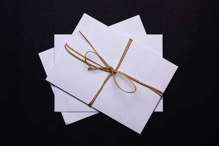 White envelopes banded with golden lace on black background. Romantic, emotion background concept.