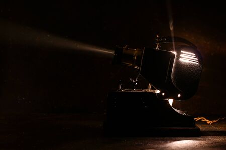 Old film projector, running and projecting with visible beam of light. Old slide projector on dark...