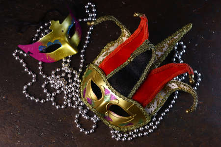 Carnival venetian Joker masks and silver beads on dark background. Carnival masks top view.の写真素材