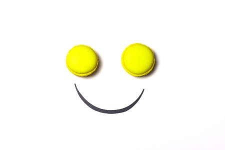 Smiley face concept. Smiley face made from macaroon on white background. Sweet smiley face metaphor.の写真素材