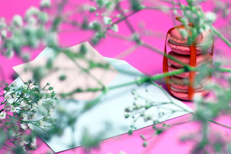 Pink macaroons with white open envelope and white wild flowers on pink background. Roman 
tic letter concept.の写真素材