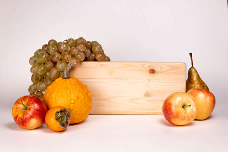 Autumn harvest fruits and wooden signboard isolated on white background. Apples, pumpkin, grape bunch, pear and kinglet.の写真素材