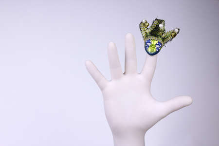 Hand with white medical glove on it wearing carnival mask. Christmas and New Year and holiday conceptの写真素材