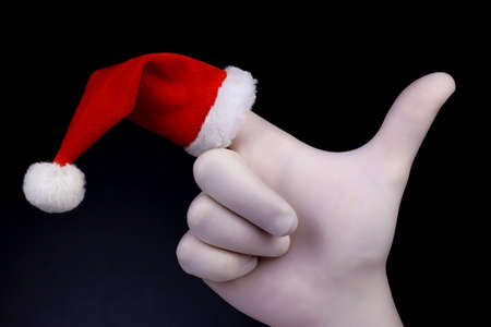 Pointing hand with Santa Claus heat on finger. Hand in white glove and Santa Claus heat pointing on black background. Christmas and New Year holidays concept.の写真素材