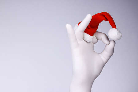Like. Hand in Santaâs hat showing like sign on white background. Hand in white glove in Santa`s hat showing OK symbol. Christmas and New Year concept.の写真素材