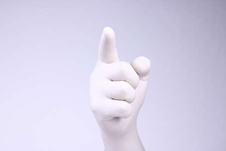 Pointing hand with white glove. Pointing male hand with medical glove on white background.の写真素材