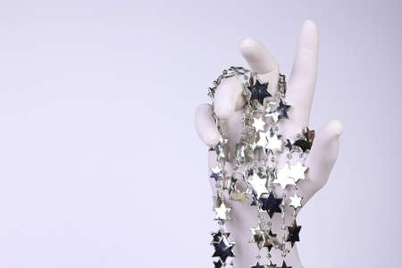 Hand with white glove holding Christmas tree stars on white background. Christmas and New Year concept. Holiday decoration composition.の写真素材