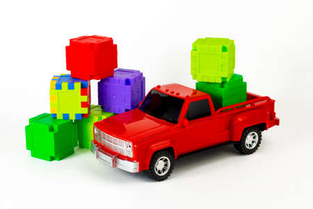 Colorful cubes in red trendy pickup trunk. Toy truck and puzzles. Contemporary construction and development concept. Part of set.の写真素材
