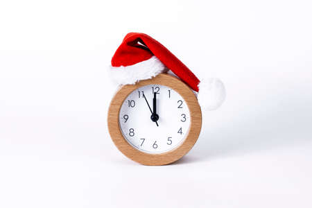 Christmas and New Year holidays time concept. Clock with Christmas Santa`s hat isolated on white...