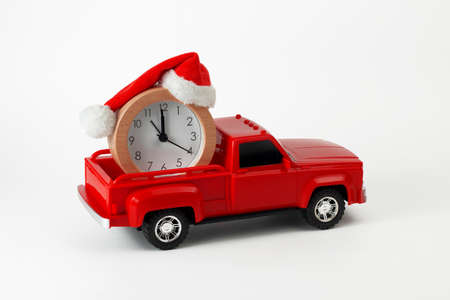 Christmas and New Year holidays time concept. Red trendy pickup toy with clock and Christmas Santa`s hat in the trunk. Part of set.の写真素材