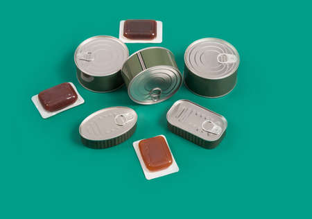 Preserve cans and terrines with food on a green background. Horizontal photography made in studio.