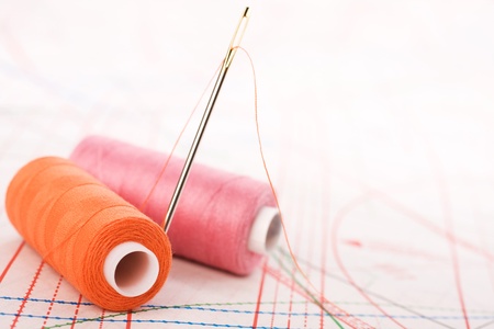 Spool of thread and needle. Sew accessories on blurred background.