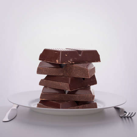 Chocolate bars stack on plate. Unhealthy eating concept.
