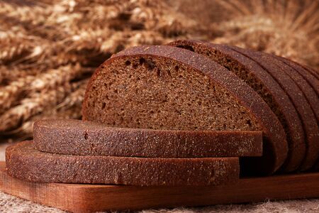 Loaf of bread and rye ears still life on rustic background