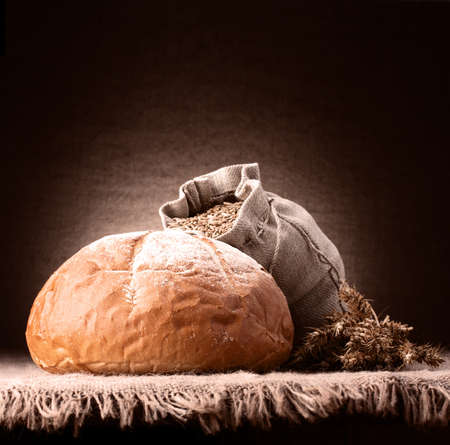 Bread, flour sack and ears bunch still life on rustic background